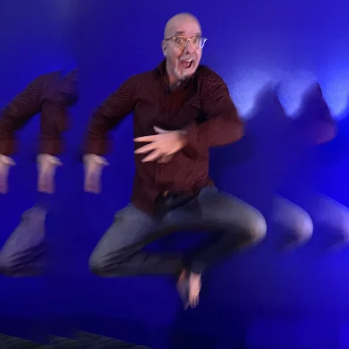 Gig Entertainer Ramp jumping in mid-air against a blue background with motion blur trails.