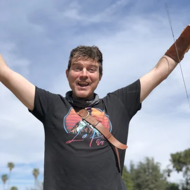 Ramp with arms raised excitedly outdoors wearing an archer's arm guard